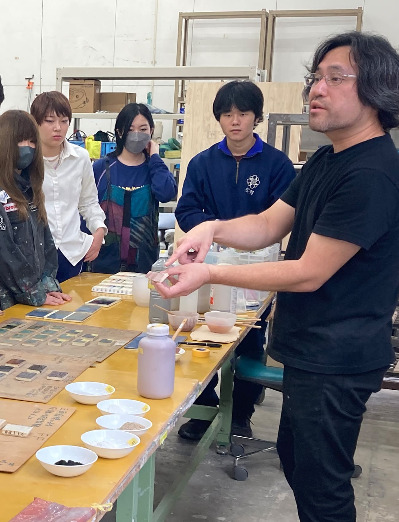 A Studio artisan teaching students mural production techniques