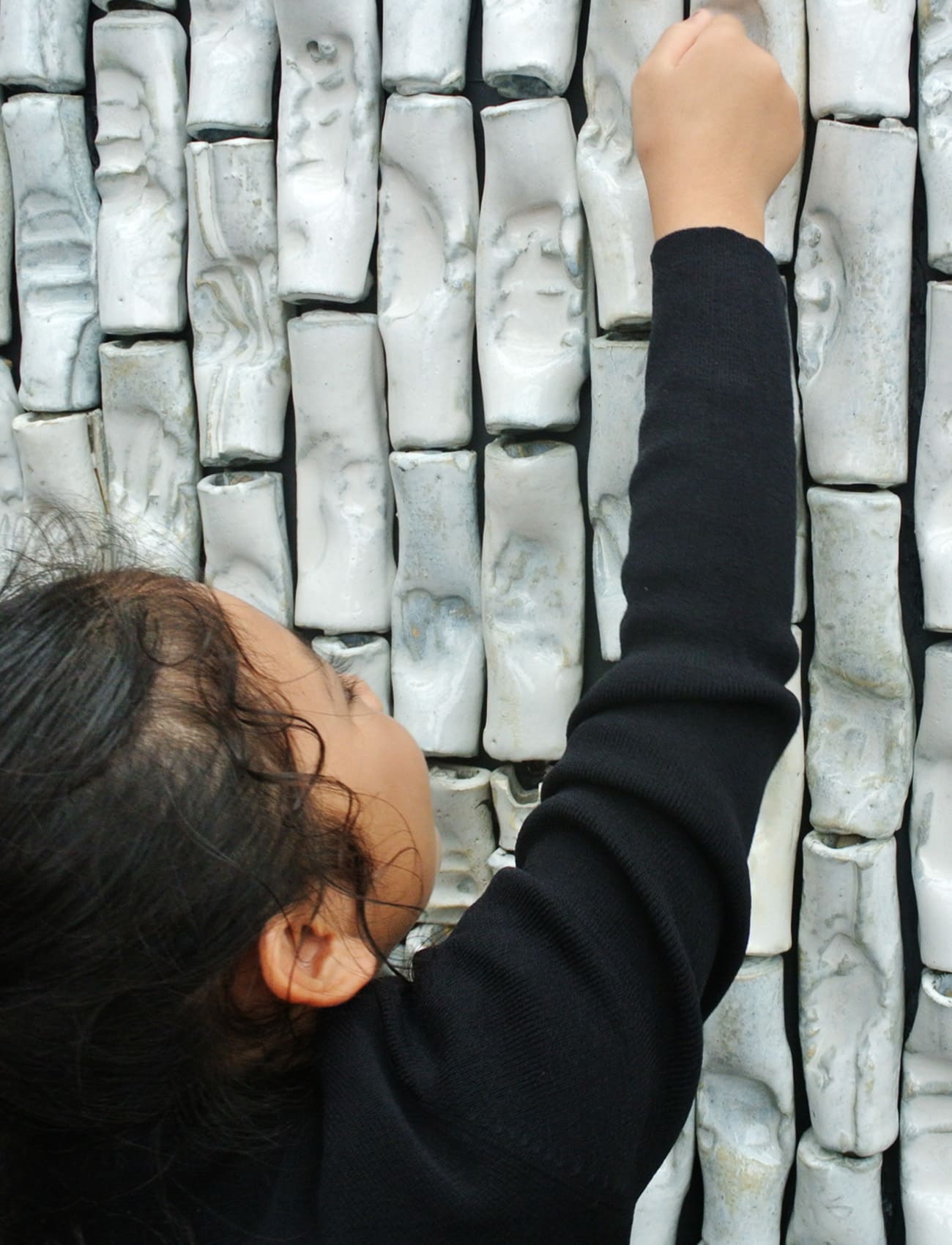 A child touching a ceramic artwork created during a workshop
