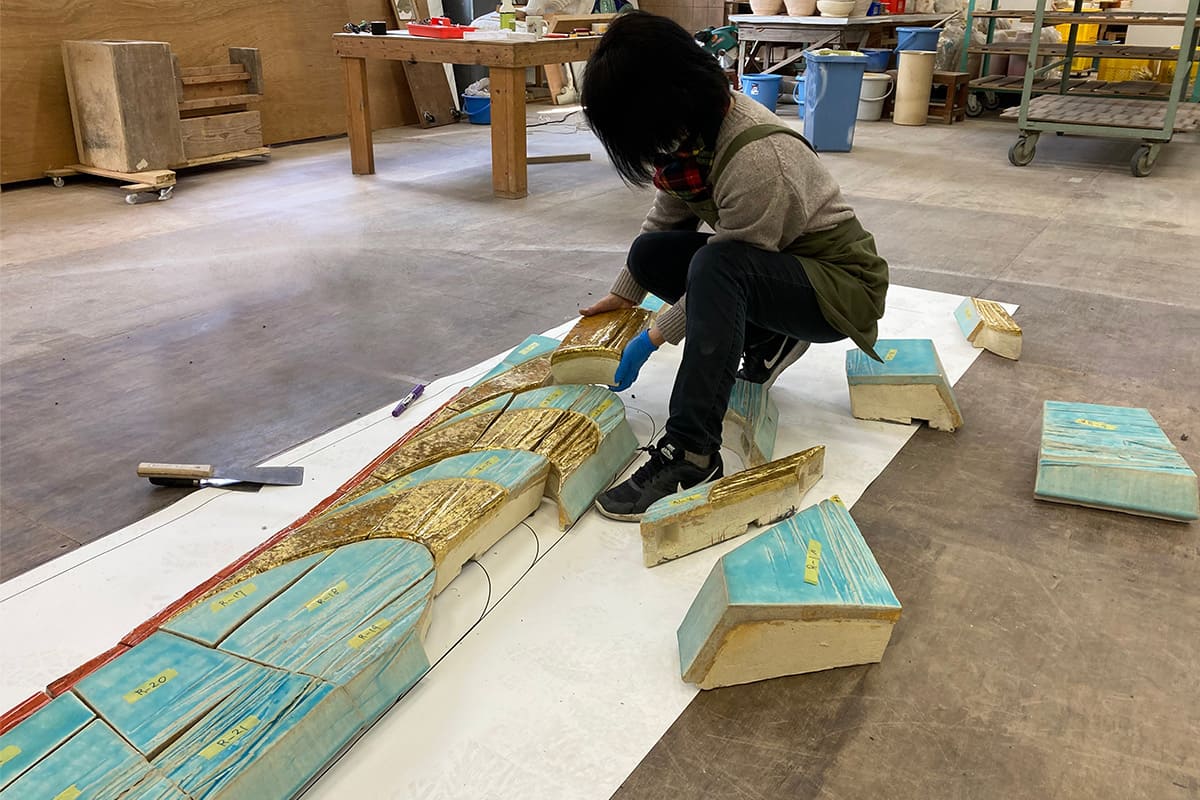 工房で陶板レリーフ作品「TO THE SKY」を修復している様子