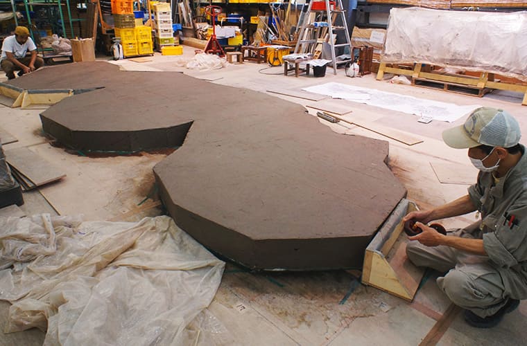 Repeatedly striking clay against the floor to create a clay slab